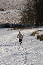 England, Jogger running in field of snow.