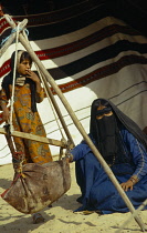 Qatar, General, Bedouin woman and daughter with water skin and traditional woven tent.