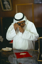 Qatar, Doha, Man examining pearls in a shop.