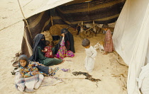 Qatar, People, Nomadic Bedouin veiled women and children sitting in entrance to tent.