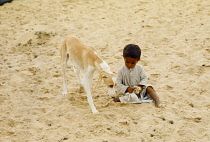 Qatar, Desert, Young Bedouin boy with Saluki dog.