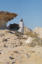Qatar, Desert, Bedouin man stood on rocky landscape.
