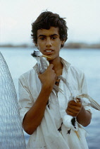 Qatar, Industry, Fishing nets boy holding birds.