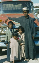 Qatar, Young brothers ands sisters stood in front of truck.