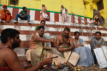 India, Uttar Pradesh, Varanasi, A pundit performs a puja for a bereaved family at Kedar Ghat.