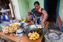India, Uttar Pradesh, Varanasi, A woman cooking fried pakora and samosas at a food hotel.