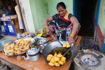 India, Uttar Pradesh, Varanasi, A woman cooking fried pakora and samosas at a food hotel.