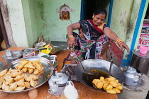 India, Uttar Pradesh, Varanasi, A woman cooking fried pakora and samosas at a food hotel.