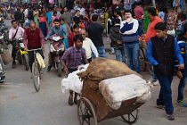 India, Uttar Pradesh, Varanasi, A man pushes a cart of waste materials to be recycled through Dasashwamedh Ghat Road.