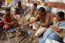 India, Uttar Pradesh, Varanasi, A pundit performs a puja for a bereaved family at Kedar Ghat.