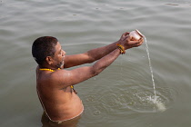 India, Uttar Pradesh, Varanasi, A pilgrim praying in the River Ganges.