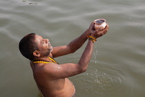 India, Uttar Pradesh, Varanasi, A pilgrim praying in the River Ganges.