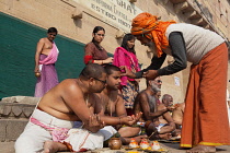 India, Uttar Pradesh, Varanasi, A saddhu performs a puja for a bereaved family on the ghats.