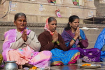 India, Uttar Pradesh, Varanasi, Hindi women praying on the ghats beside the River Ganges.