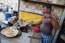 India, Uttar Pradesh, Varanasi, A cook making tandoori roti at a food hotel.