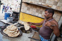 India, Uttar Pradesh, Varanasi, A cook making tandoori roti at a food hotel.