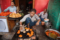 India, Uttar Pradesh, Faizabad, A cook frying jalebis at a food hotel.