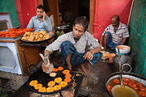 India, Uttar Pradesh, Faizabad, A cook frying jalebis at a food hotel.
