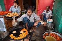 India, Uttar Pradesh, Faizabad, A cook frying jalebis at a food hotel.