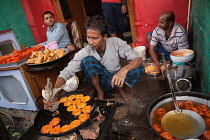 India, Uttar Pradesh, Faizabad, A cook frying jalebis at a food hotel.