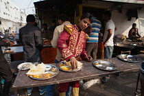 India, Uttar Pradesh, Lucknow, A man wearing his Band uniform eats a thali at a food hotel.