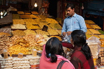 India, Uttar Pradesh, Lucknow, A vendor serves customers at his namkeen & savoury snacks stall.