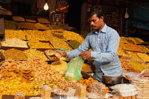 India, Uttar Pradesh, Lucknow, A vendor serves at his namkeen & savoury snacks stall.