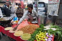 India, Uttar Pradesh, Lucknow, A vendor prepares a vegetarian snack including mung bean srouts at his road-side stall.