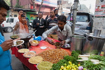 India, Uttar Pradesh, Lucknow, A vendor prepares a vegetarian snack including mung bean srouts at his road-side stall.