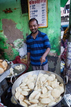 India, New Delhi, A cook frying kachori at a street stall in the old city of Delhi.