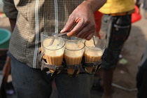 India, New Delhi, A chai vendor carrying glasses of tea.