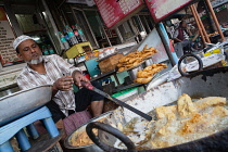 India, New Delhi, Muslim cook frying battered pieces of chicken at a food hotel in the old city of Delhi.