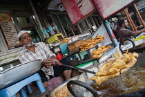 India, New Delhi, Muslim cook frying battered pieces of chicken at a food hotel in the old city of Delhi.
