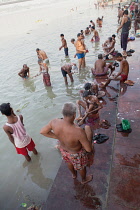 India, West Bengal, Kolkata, Men wash and bathe in the Hooghly River at Malik Ghat.