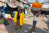 India, West Bengal, Kolkata, Men carrying garlands of marigolds through Malik Ghat flower market.
