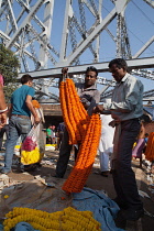 India, West Bengal, Kolkata, Malik Ghat flower market in with Howrah Bridge in the background.