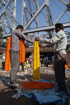 India, West Bengal, Kolkata, Malik Ghat flower market in with Howrah Bridge in the background.