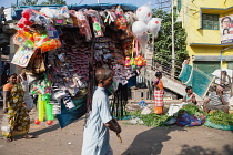 India, West Bengal, Kolkata, A vendor selling toys and fashion accessories walks through Malik Ghat flower market.