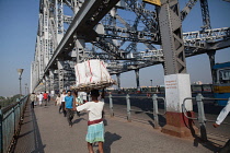 India, West Bengal, Kolkata, Howrah Bridge, Man carrying goods on his head.