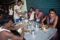 India, West Bengal, Kolkata, Men eat a thali meal of rice and dal at a food hotel.