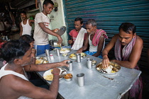 India, West Bengal, Kolkata, Men eat a thali meal of rice and dal at a food hotel.