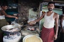 India, Uttar Pradesh, Kolkata, A cook fries onions at a food hotel.