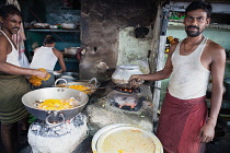 India, West Bengal, Kolkata, A cook fries onions at a food hotel.