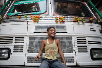 India, West Bengal, Kolkata, A smiling boy sits on the front of a truck.