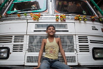 India, West Bengal, Kolkata, A smiling boy sits on the front of a truck.