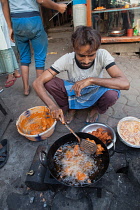 India, West Bengal, Kolkata, A man cooks chicken pakora on the street.