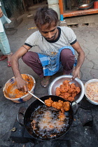 India, West Bengal, Kolkata, A man cooks chicken pakora on the street.