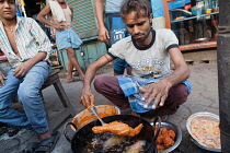 India, West Bengal, Kolkata, A man cooks chicken pakora on the street.