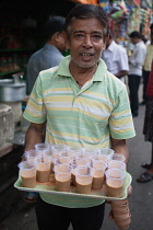 India, West Bengal, Kolkata, Chai vendor with a tray of tea in plastic cups in Sudder Street,.