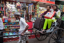 India, West Bengal, Kolkata, A rickshaw driver pulls passengers through the streets.
